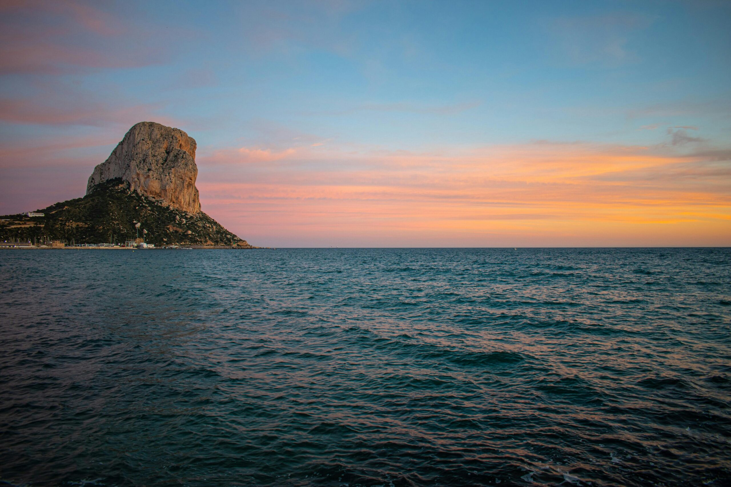 Breathtaking golden hour view over the ocean, featuring a striking rock formation.