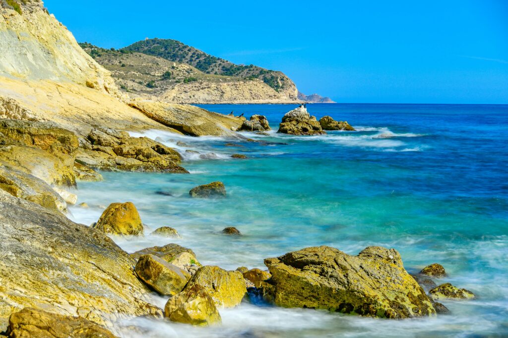 Breathtaking view of the rocky coastline in Villajoyosa, Spain with clear blue water and dramatic landscapes.