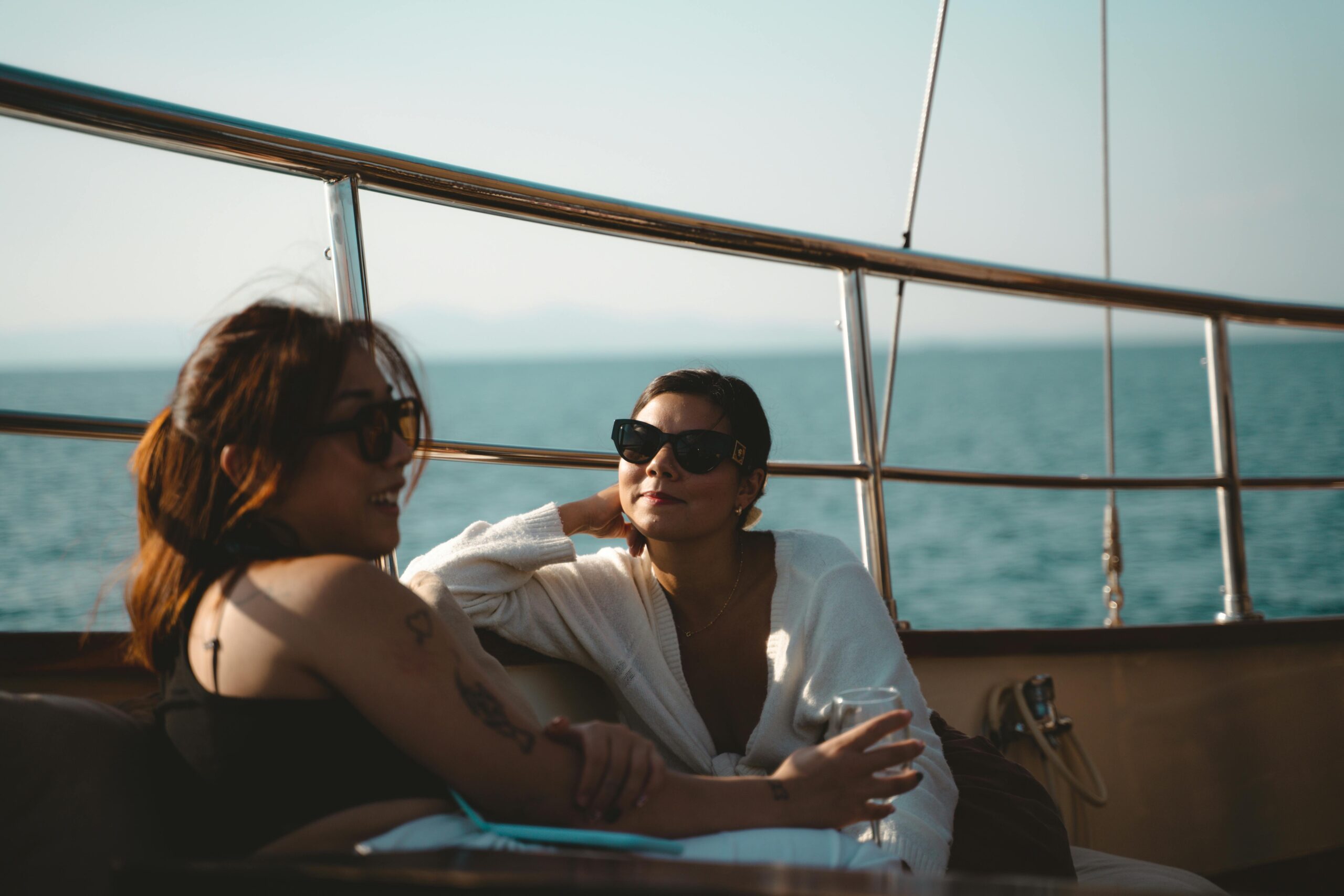 Two women enjoying a relaxing time on a yacht at sunset, reflecting leisure and summer vibes.