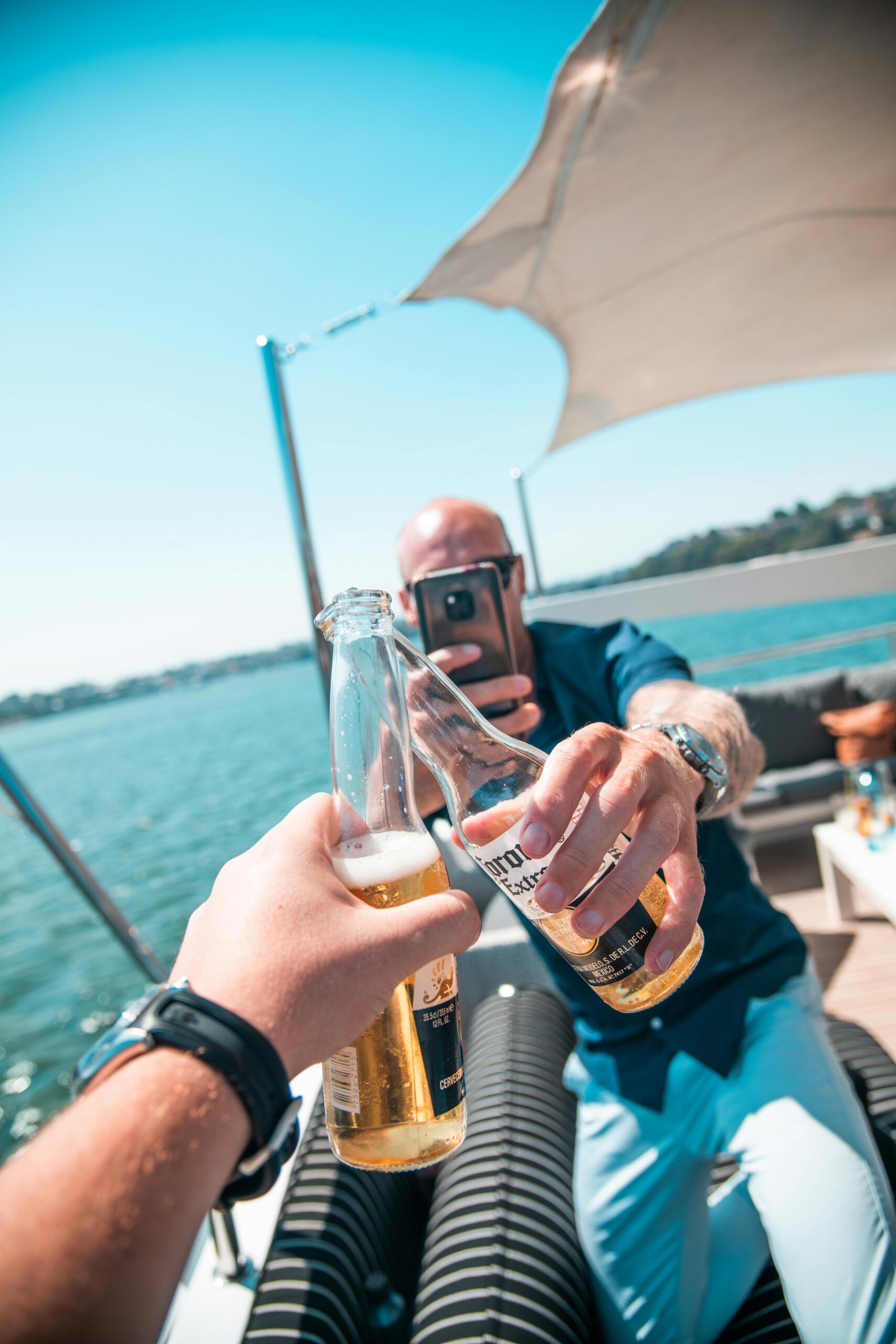 Two friends enjoying a beer toast on a boat in sunny Sydney, Australia.